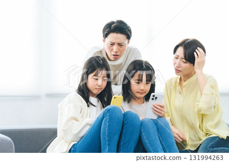 Family of elementary school girl with troubled expression looking at smartphone 131994263