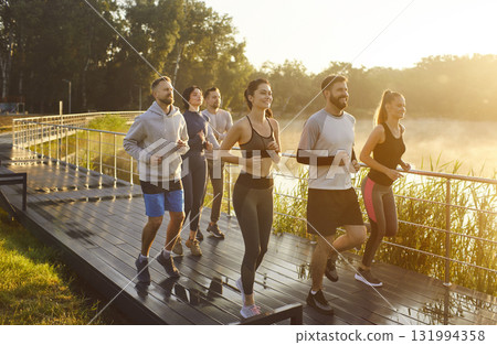 Running friends jogging as group in park by lake, runners in sportswear training Running friends jogging as group in park by lake, runners in sportswear training 131994358