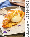 A sweet and crispy croissant filled with a scoop of vanilla ice cream 131994362