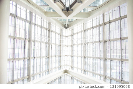 Bright, modern architectural detail featuring a glass and steel atrium ceiling. The symmetrical design creates a clean, bright, and inspiring corporate or public space. Bright, modern architectural detail featuring a glass and steel atrium ceiling. The symmetrical design creates a clean, bright, and inspiring corporate or public space. 131995068