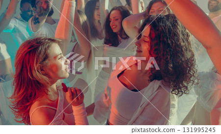 Smiling friends dancing together in soft white light of Valentine party night Smiling friends dancing together in soft white light of Valentine party night 131995245