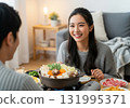 A woman with a genuine smile as she sits around a hotpot with her husband 131995371