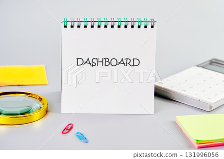 DASHBOARD word written in a notebook in a composition with a calculator, a magnifying glass, and stickers. Data Analysis for Business and Finance Concept 131996056