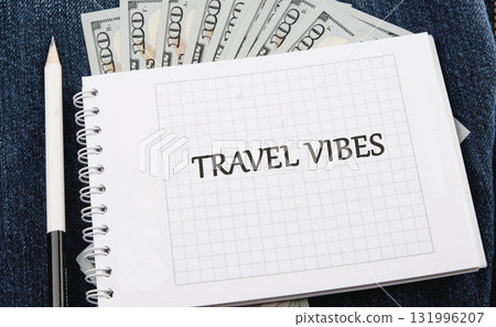 A spiral notepad with TRAVEL VIBES written on it sits on a denim surface with a pencil and a stack of cash, sparking ideas for future trips and exciting escapades A spiral notepad with TRAVEL VIBES written on it sits on a denim surface with a pencil and a stack of cash, sparking ideas for future trips and exciting escapades 131996207