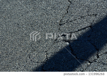 Cracked asphalt and diagonal black shadows. Urban background material 131996268