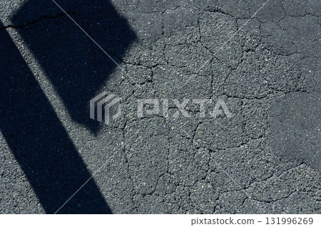 Cracked asphalt and diagonal black shadows. Urban background material Cracked asphalt and diagonal black shadows. Urban background material 131996269