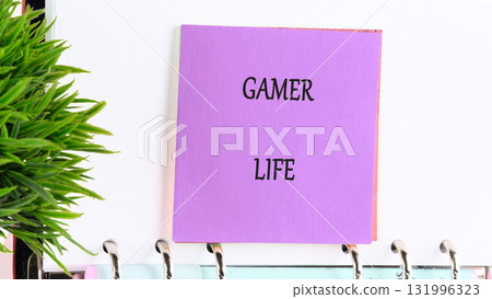 A purple note with GAMER LIFE written in black letters hangs from a ringed notebook. A green plant sits to the left, creating a bright and clean workspace 131996323