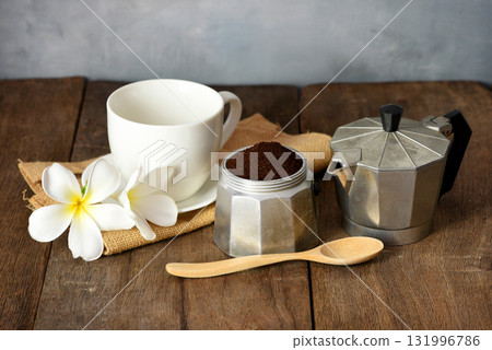 Prepare morning coffee with a Moka pot on a wooden table decorated with flowers. 131996786