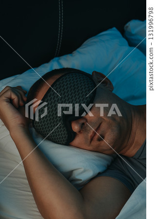 closeup of a man wearing a sleep mask in bed 131996798