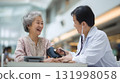 young asian doctor checking blood pressure of elderly patient in modern clinic neutral tones 131998058