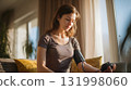 young woman measuring blood pressure with digital monitor in cozy living room warm daylight 131998060