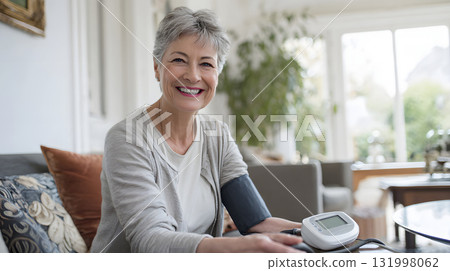 smiling woman measuring blood pressure with modern digital device in living room 131998062