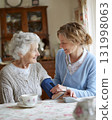 elderly woman assisted by caregiver while checking blood pressure warm family scene 131998063