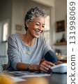 middle aged woman using blood pressure monitor on desk with soft daylight 131998069