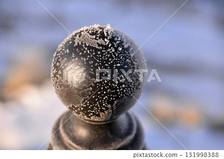 Ice crystals and snowflakes on a metal ball 131998388