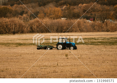 blue tractor drives across an autumn field, copy space 131998571