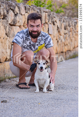 Man grooming Jack Russell Terrier outdoors brushing coat to reduce shedding 131999374
