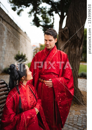 Interracial couple celebrating traditional Chinese wedding wearing red hanfu Interracial couple celebrating traditional Chinese wedding wearing red hanfu 131999638