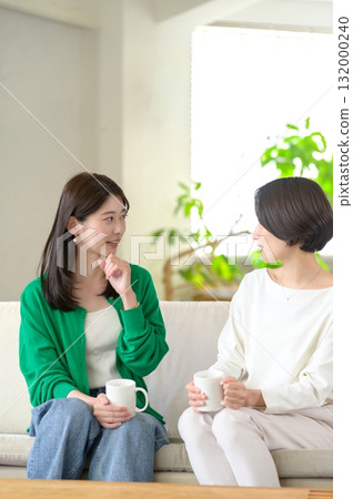Women sitting on a sofa and having a conversation 132000240