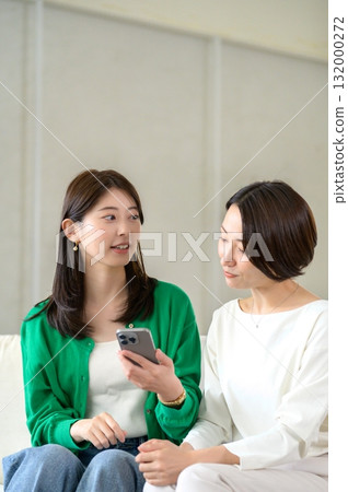 Women sitting on a sofa and having a conversation Women sitting on a sofa and having a conversation 132000272