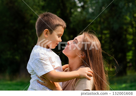 Sweet mother-son moment. 6 years old boy and his mom share tender nose to nose kiss. Heartwarming display of unconditional love and family bonding. 132001608