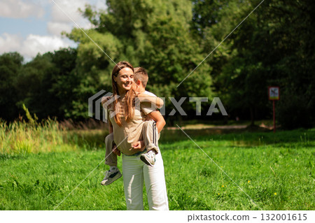 Adorable mother-son duo playing dancing joyfully outside in park. Pure happiness and playful bonding. Candid family moment. 132001615