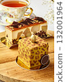 Delicious modern cakes with gold decorations resting on wooden table near teacup 132001964