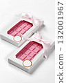 Two pink chocolate bars wrapped with pink ribbon in white box on white background 132001967
