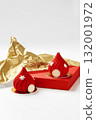 Two red christmas mousse cakes decorated with snowflakes and gold details resting on red surface with gold wrapping paper 132001972