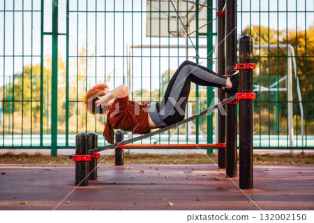Side view of mid adult woman does abdominal crunches lies on bench training in city park. Copy space. Concept of fitness and sport Side view of mid adult woman does abdominal crunches lies on bench training in city park. Copy space. Concept of fitness and sport 132002150