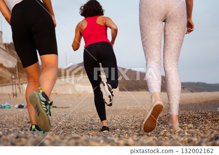 Wellness. Back bottom view of group of jogging women at pebble beach. Close up of feet. Concept of healthy lifestyle and cardio fitness Wellness. Back bottom view of group of jogging women at pebble beach. Close up of feet. Concept of healthy lifestyle and cardio fitness 132002162