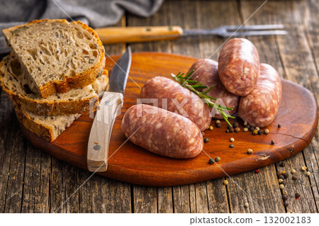 Photo of italian sausage salsiccia on cutting board on wooden table. Photo of italian sausage salsiccia on cutting board on wooden table. 132002183