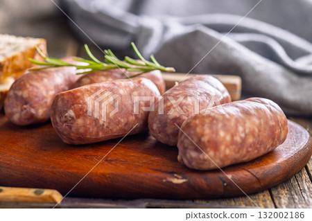 Photo of italian sausage salsiccia on cutting board on wooden table. Photo of italian sausage salsiccia on cutting board on wooden table. 132002186