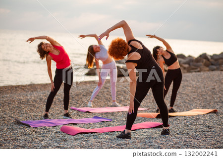 Group of young athletic women are training on sports mats on beach. Concept of sports and health Group of young athletic women are training on sports mats on beach. Concept of sports and health 132002241