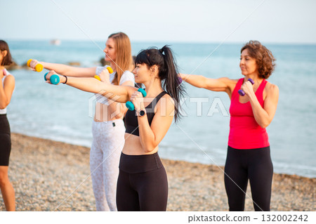 Group of adult Caucasian women training with dumbbells. Concept of fitness and yoga Group of adult Caucasian women training with dumbbells. Concept of fitness and yoga 132002242