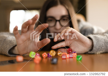 Young woman smiling while destroying a pyramid of dice. Concept of play fun and imperfection. 132002792