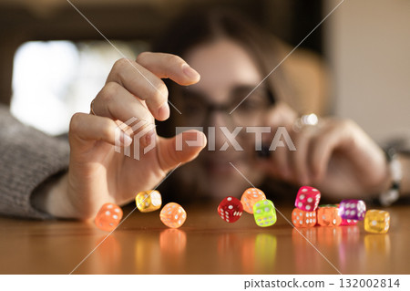 Woman stacking dice one on another on the table in front of her face. Concept of focus creativity and patience. Woman stacking dice one on another on the table in front of her face. Concept of focus creativity and patience. 132002814