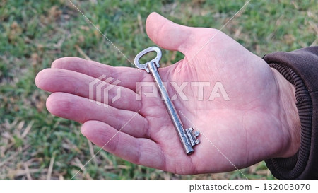 closeup. hand holding a vintage key. hand holding a key. hand holds vintage key tightly closeup. hand holding a vintage key. hand holding a key. hand holds vintage key tightly 132003070