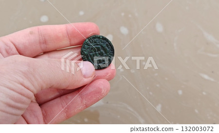 hand holds an antique coin. concept of archaeological excavations. hand holds an antique coin. concept of archaeological excavations. 132003072