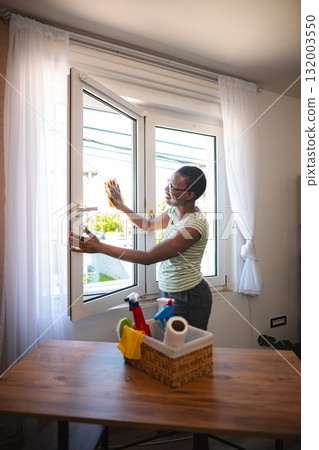 Housekeeper cleaning windows in a modern apartment 132003550