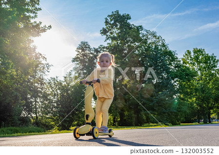 Child riding. Scooter toddler park play. Summer road motion casual sport. Child riding. Scooter toddler park play. Summer road motion casual sport. 132003552