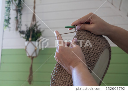 Hands crafting knitted basket with crochet hook in cozy home setting 132003792