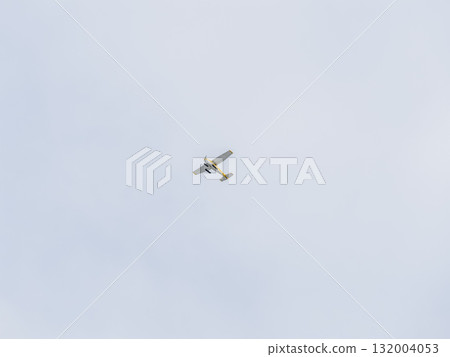 Small ultralight airplane with overhead wing and single propeller flying in sunset sky. 132004053