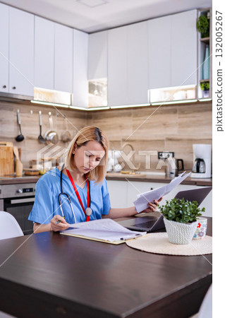 Female doctor working from home checking medical records 132005267
