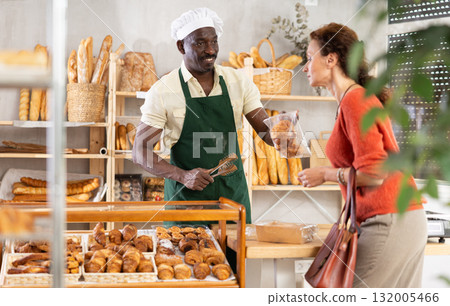Man baker packaging croissants in a plastic bag for customer Man baker packaging croissants in a plastic bag for customer 132005466