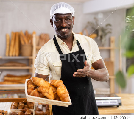 Male baker holding a tray of freshly baked croissants 132005594
