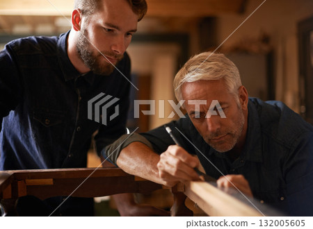 Teaching, learning and carpentry apprentice and help with pencil in designer furniture manufacturing workshop. Mentorship, carpenter and young man, wood and teamwork at sustainable business project. 132005605