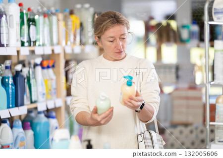 Adult woman buyer chooses liquid soap in store Adult woman buyer chooses liquid soap in store 132005606