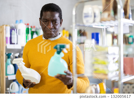 Male shopper carefully selects a spray glass cleaner for windows in home 132005617