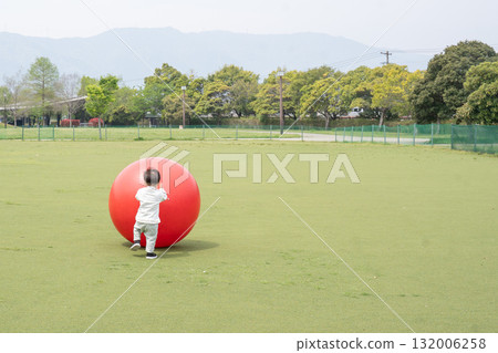 Boy rolling a big ball Boy rolling a big ball 132006258